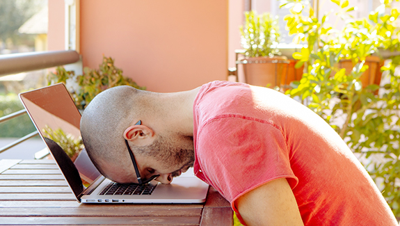 A man with his head down on the his laptop keyboard