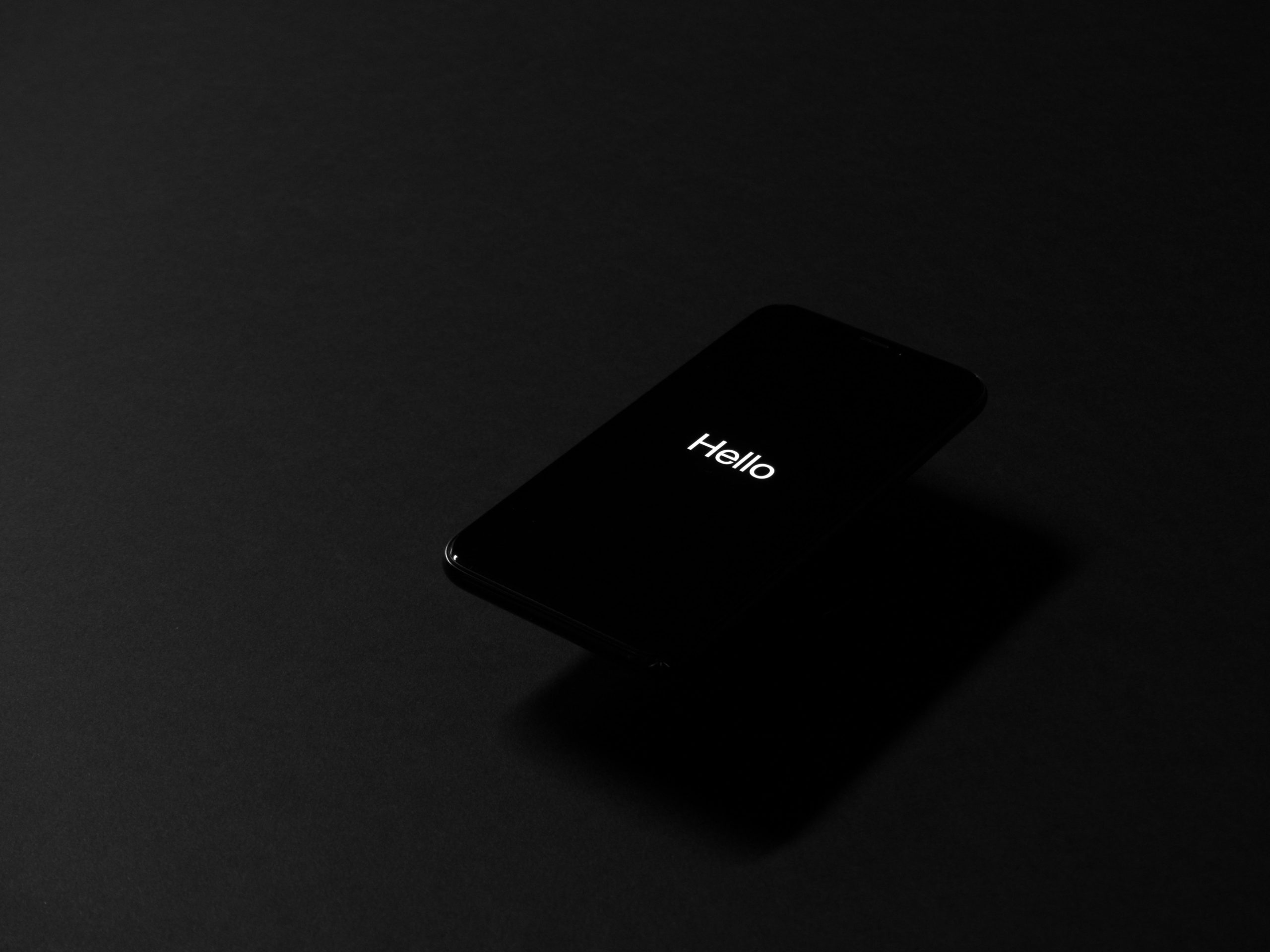 Simple message smartphone martphone screen glowing with the word “Hello” against a dark background.