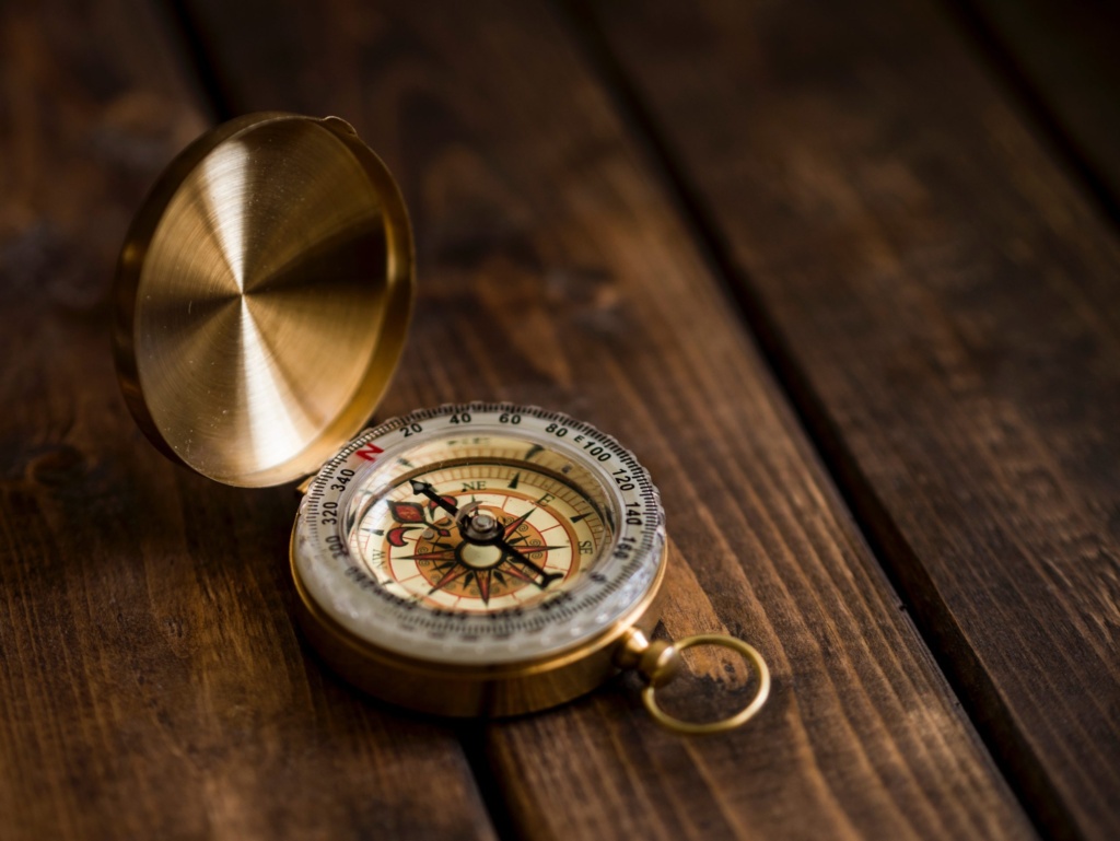 Compass Brass compass open on a wooden table, symbolizing direction and guidance.