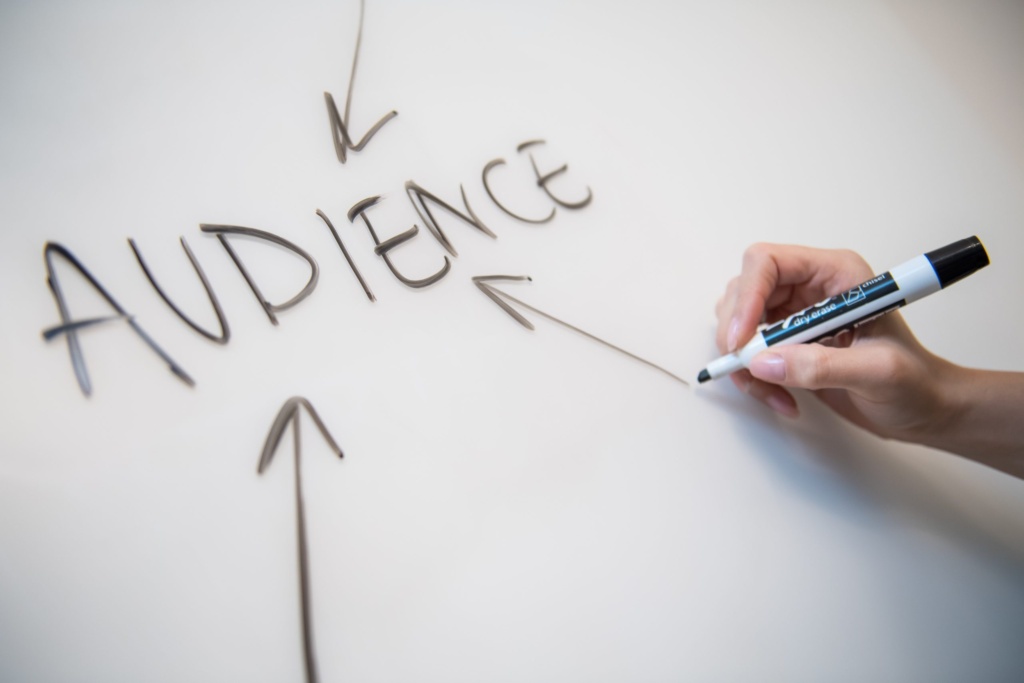 Audience-focused content strategy Person writing the word “Audience” with arrows on a whiteboard, highlighting focus on engagement.