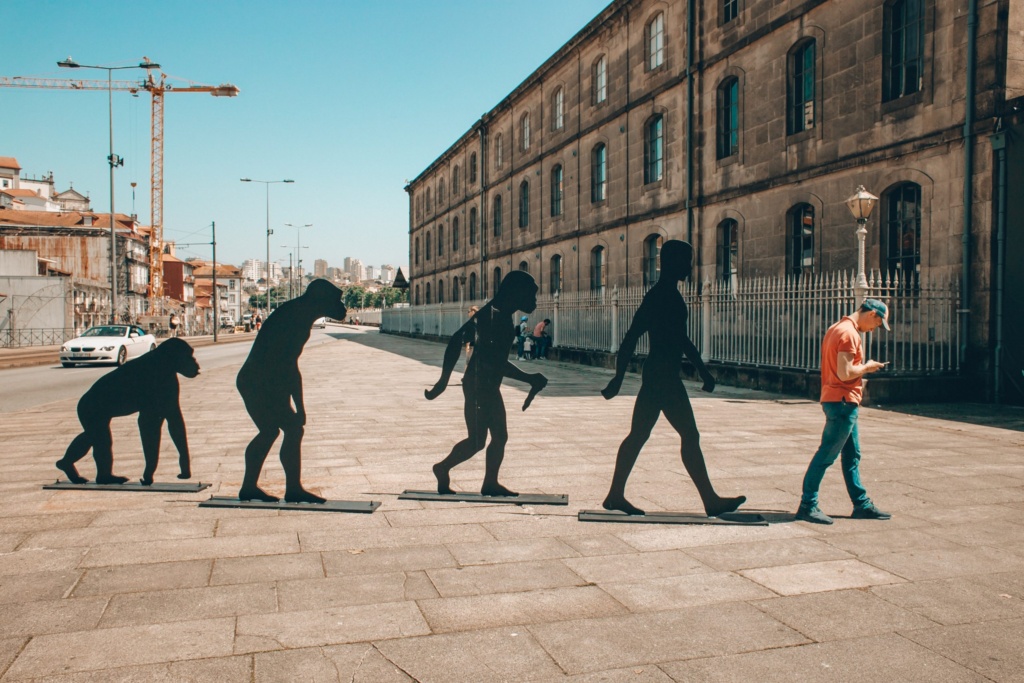 Evolution of identity street art. Street installation depicting evolution stages ending with a modern man looking at his phone.