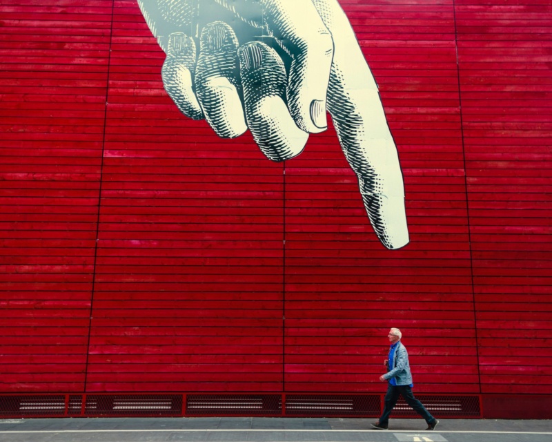 Animated giant hand pointing at a man walking to represent that custom websites are better than templated websites.