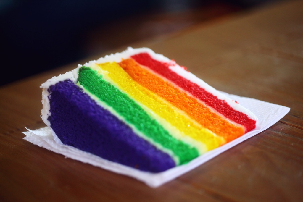 Rainbow cake slice Slice of rainbow layer cake with red, orange, yellow, green, and purple layers.