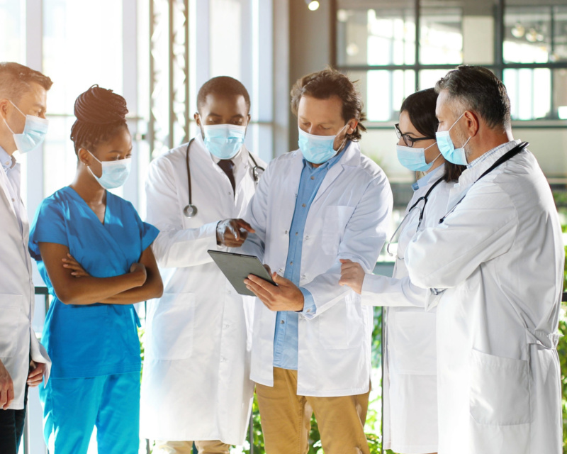 six healthcare professionals standing together looking at notes