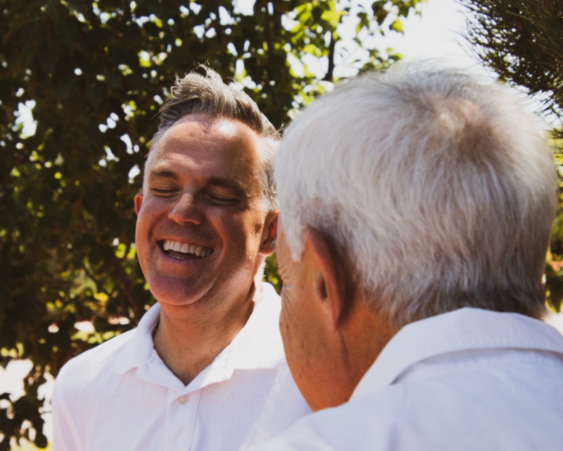 Younger man laughing hard at something an older man said to him.