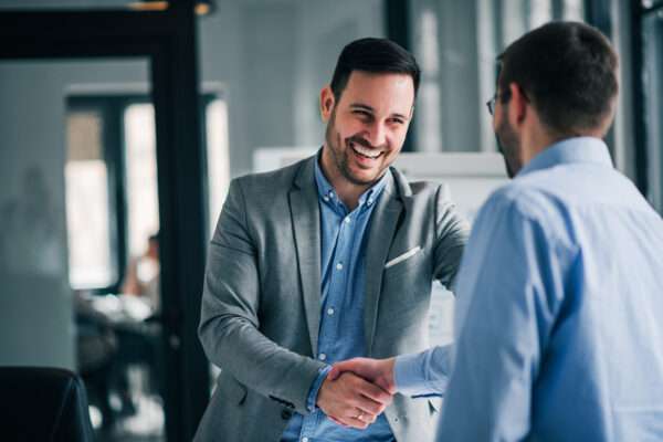 Successful business partnership handshake Two business professionals shaking hands in an office setting, smiling in agreement.