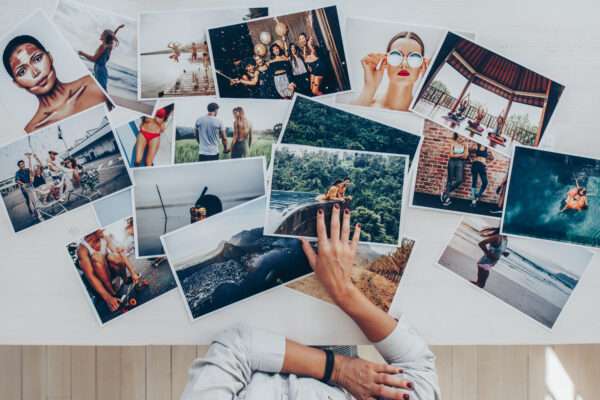 Collection of printed photos for building a healthcare brand library Person arranging printed photographs on a table, showcasing diverse lifestyle and travel images.