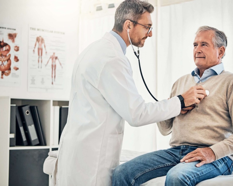 A doctor using a stethoscope to listen to his patients heart