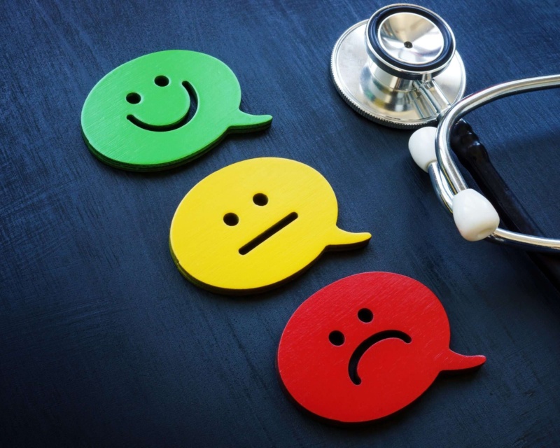 A stethoscope with three different faces next to it to showcase having a good, mediocre or bad experience