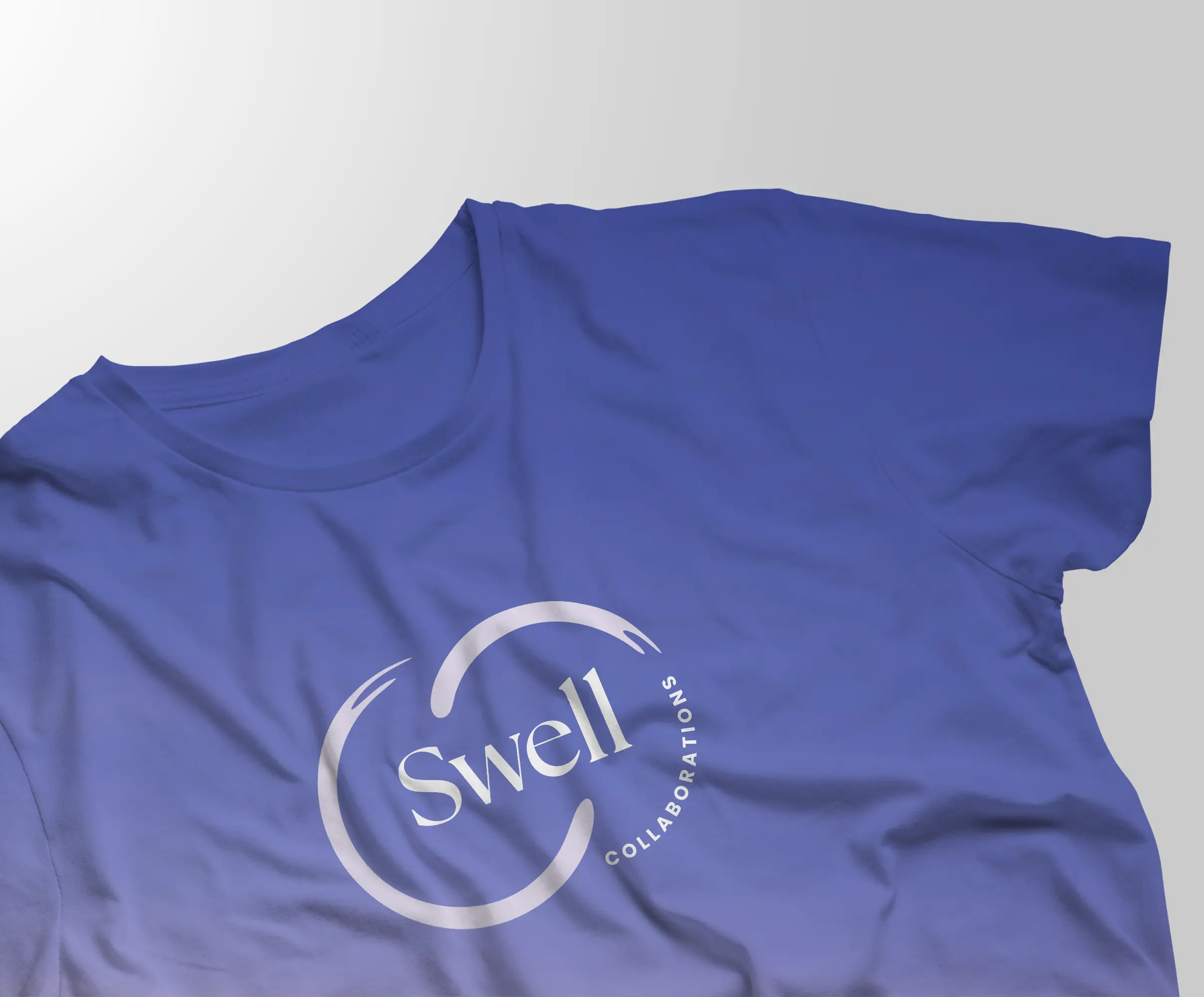 Blue t-shirt featuring the Swell Collaborations logo in white, showcasing the brand’s visual identity applied to apparel